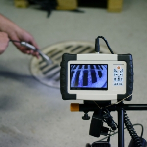 Technician feeding scope into sewer and monitoring his findings on camera.